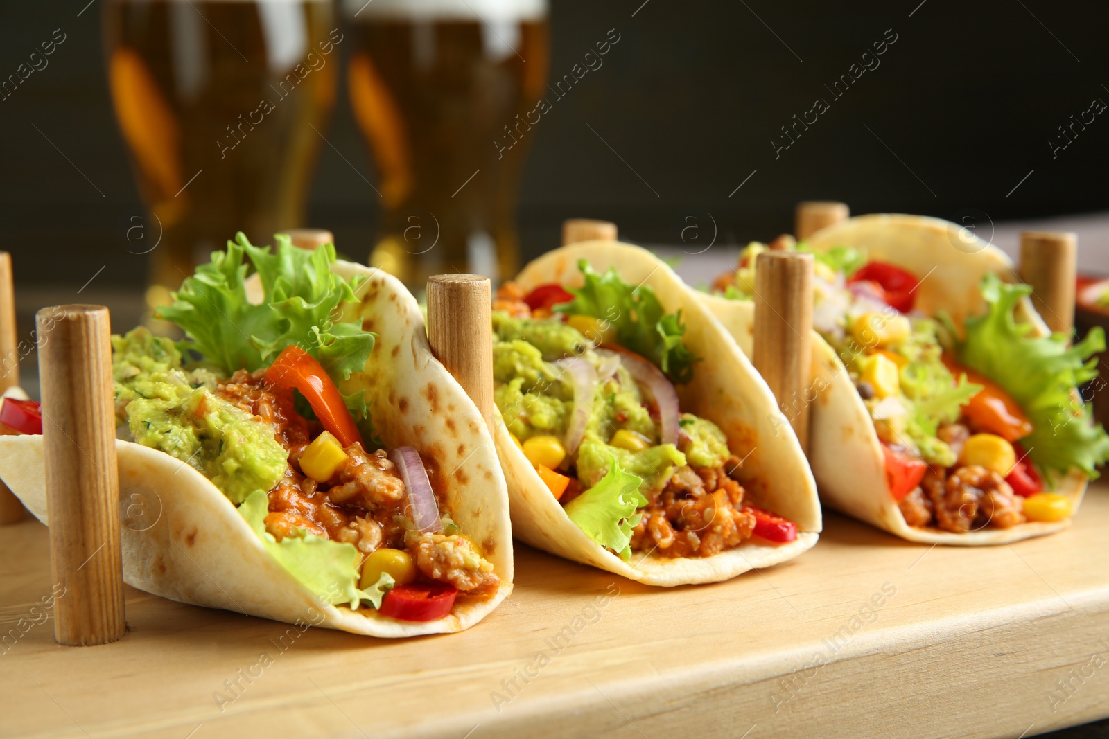 Photo of Delicious tacos with guacamole, meat and vegetables served on table, closeup