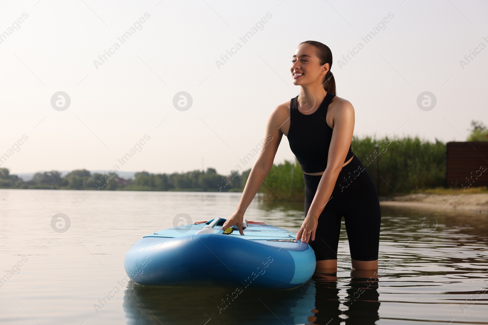 Photo of Woman standing near SUP board in water, space for text