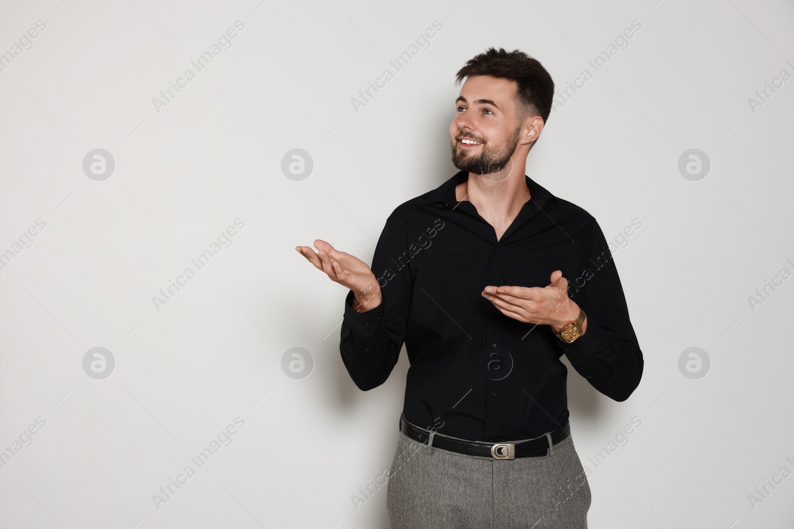 Photo of Handsome man in black shirt on light grey background, space for text