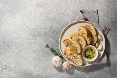 Photo of Tasty baguette with garlic and dill served on grey textured table, top view. Space for text