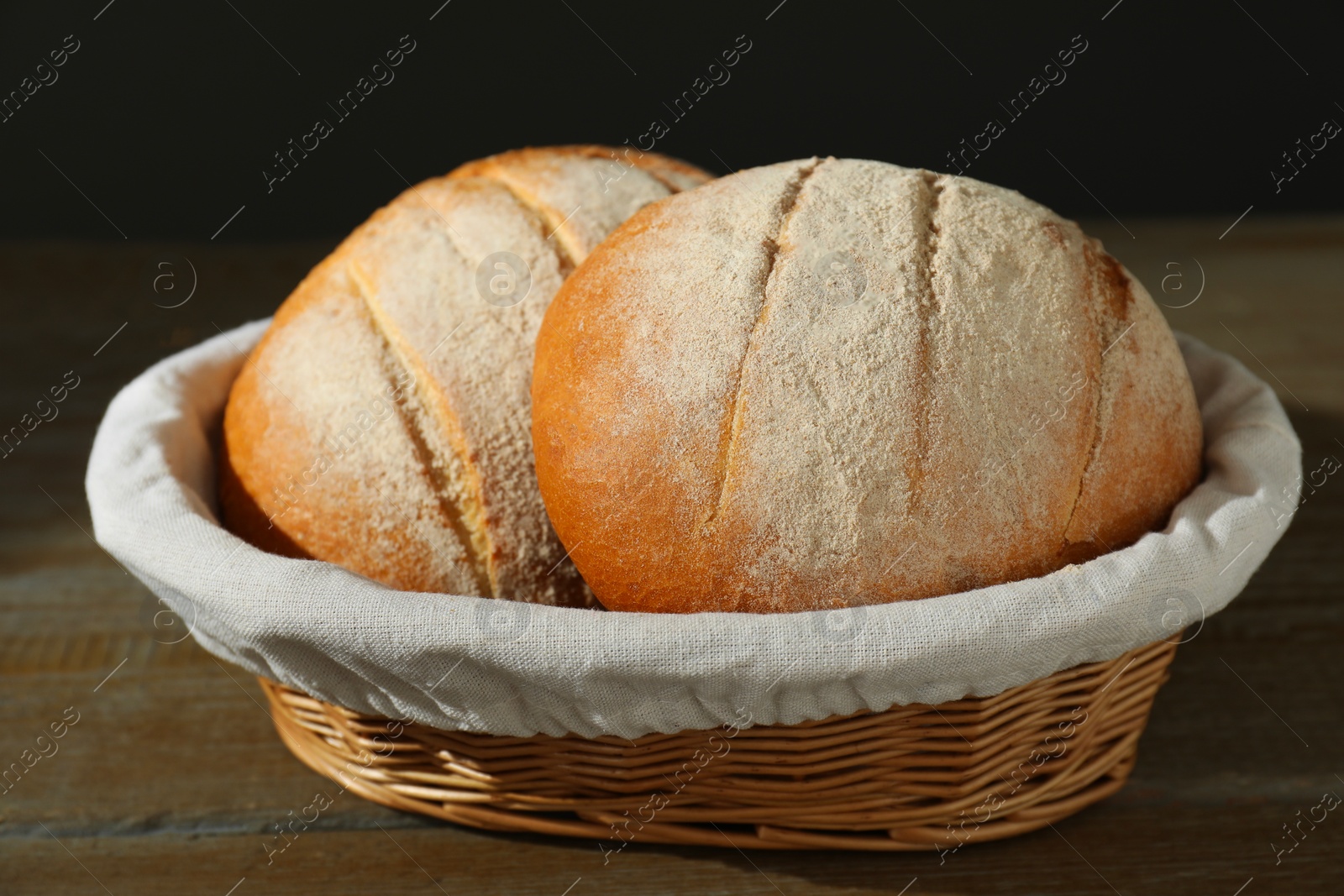 Photo of Wicker basket with fresh bread on wooden table, closeup