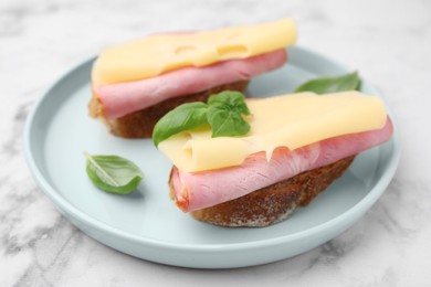 Photo of Delicious sandwiches with ham and cheese on white marble table, closeup