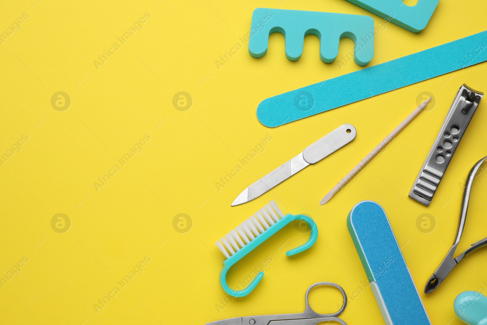 Photo of Set of pedicure tools on yellow background, flat lay. Space for text