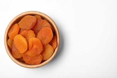 Photo of Wooden bowl of dried apricots on white background, top view with space for text. Healthy fruit