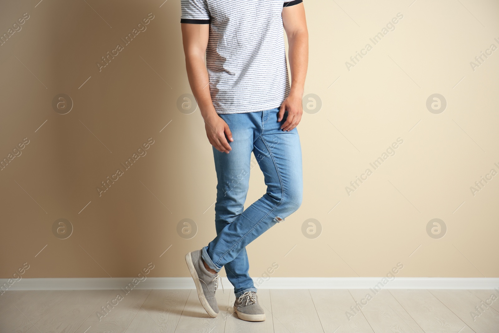 Photo of Young man in stylish jeans near light wall