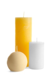 Photo of New wax candles of different shapes on white background