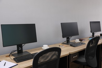 Open office interior. Modern workplaces with computers near light grey wall