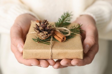 Photo of Woman holding beautifully wrapped Christmas gift box, closeup