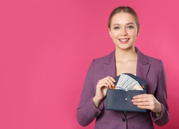 Photo of Happy young businesswoman with wallet full of money on color background. Space for text