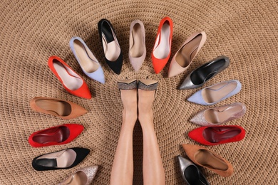 Photo of Young woman and different stylish shoes on wicker mat, top view