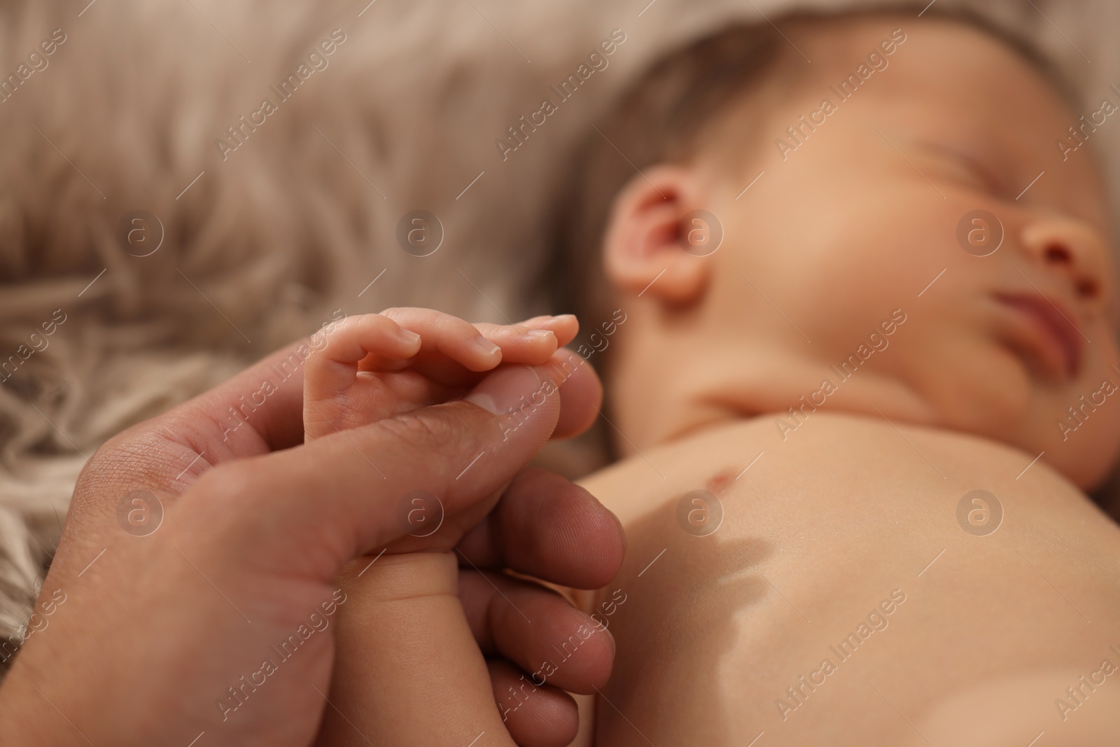 Photo of Father holding hand of his newborn baby, closeup. Lovely family