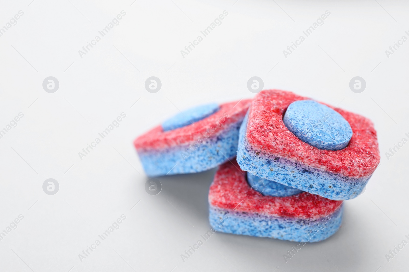 Photo of Dishwasher detergent tablets on light background, closeup. Space for text