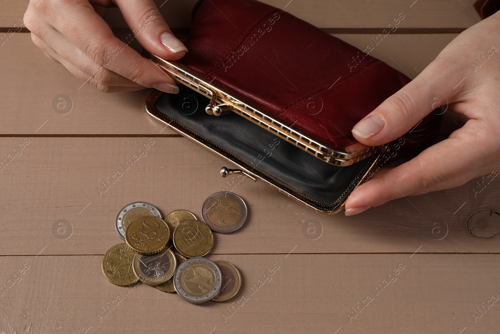 Photo of Poverty. Woman with empty wallet and coins at wooden table, above view