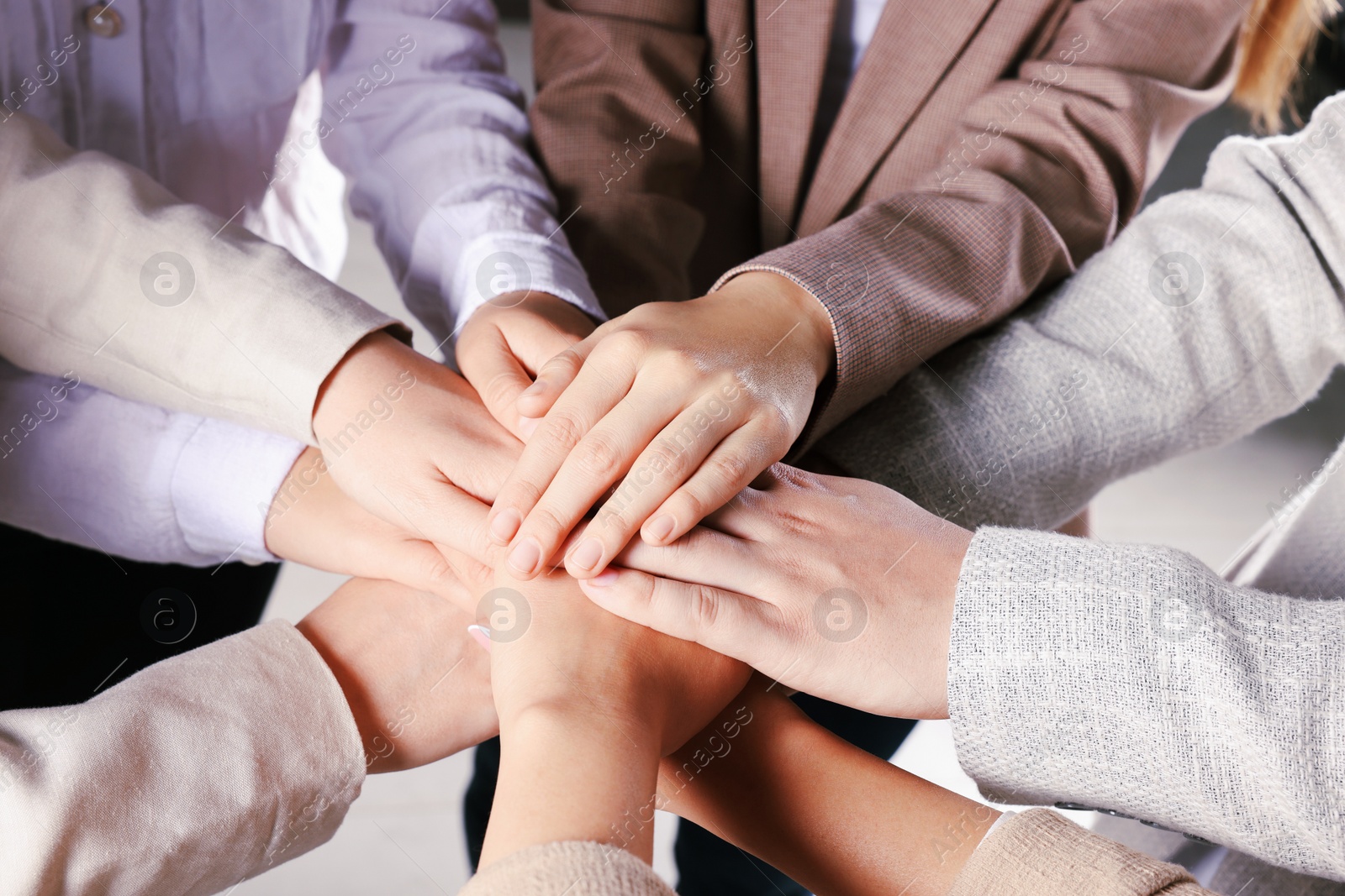 Photo of Group of people holding hands together indoors, closeup. Unity concept