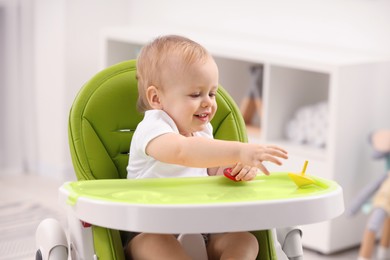 Children toys. Cute little boy playing with spinning tops in high chair at home