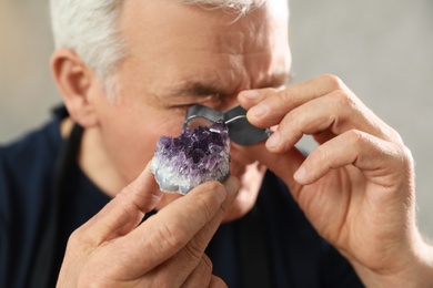 Male jeweler evaluating semi precious gemstone in workshop, closeup