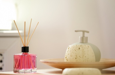 Photo of Aromatic reed air freshener and toiletries on table indoors