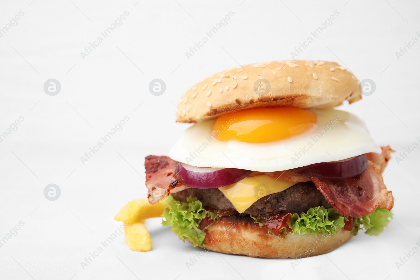 Photo of Delicious burger with fried egg on white tiled table, closeup. Space for text