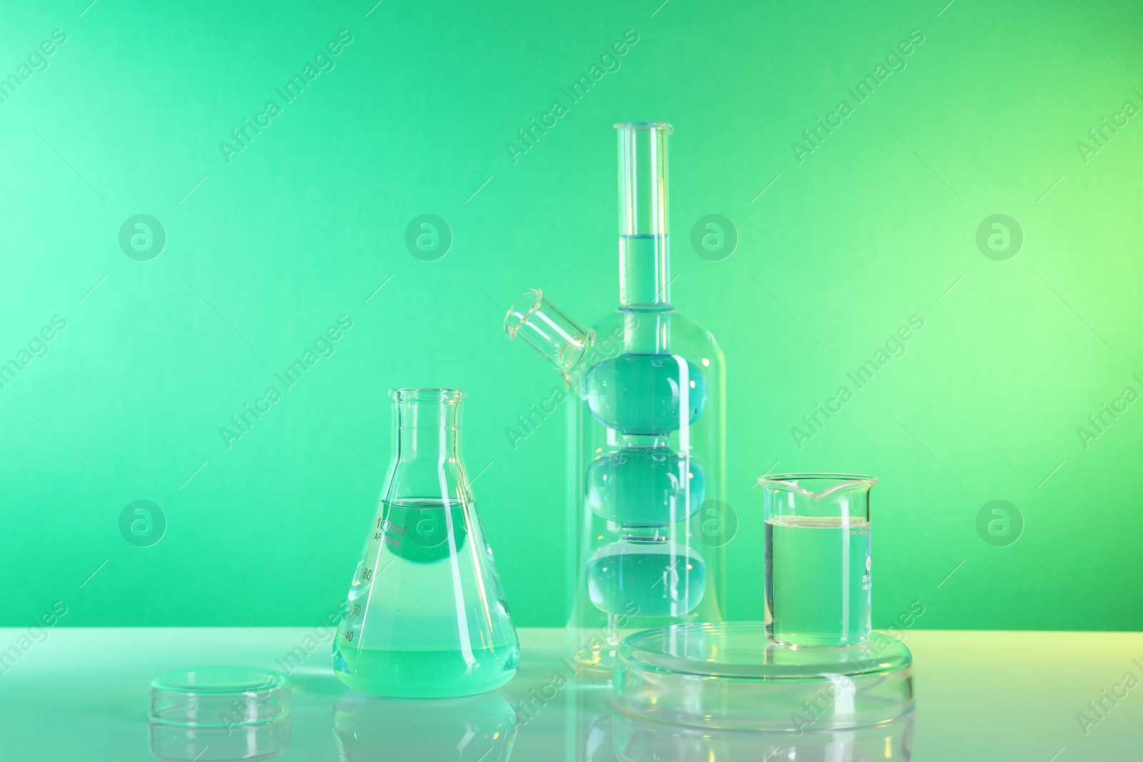 Photo of Laboratory analysis. Different glassware on table against green background