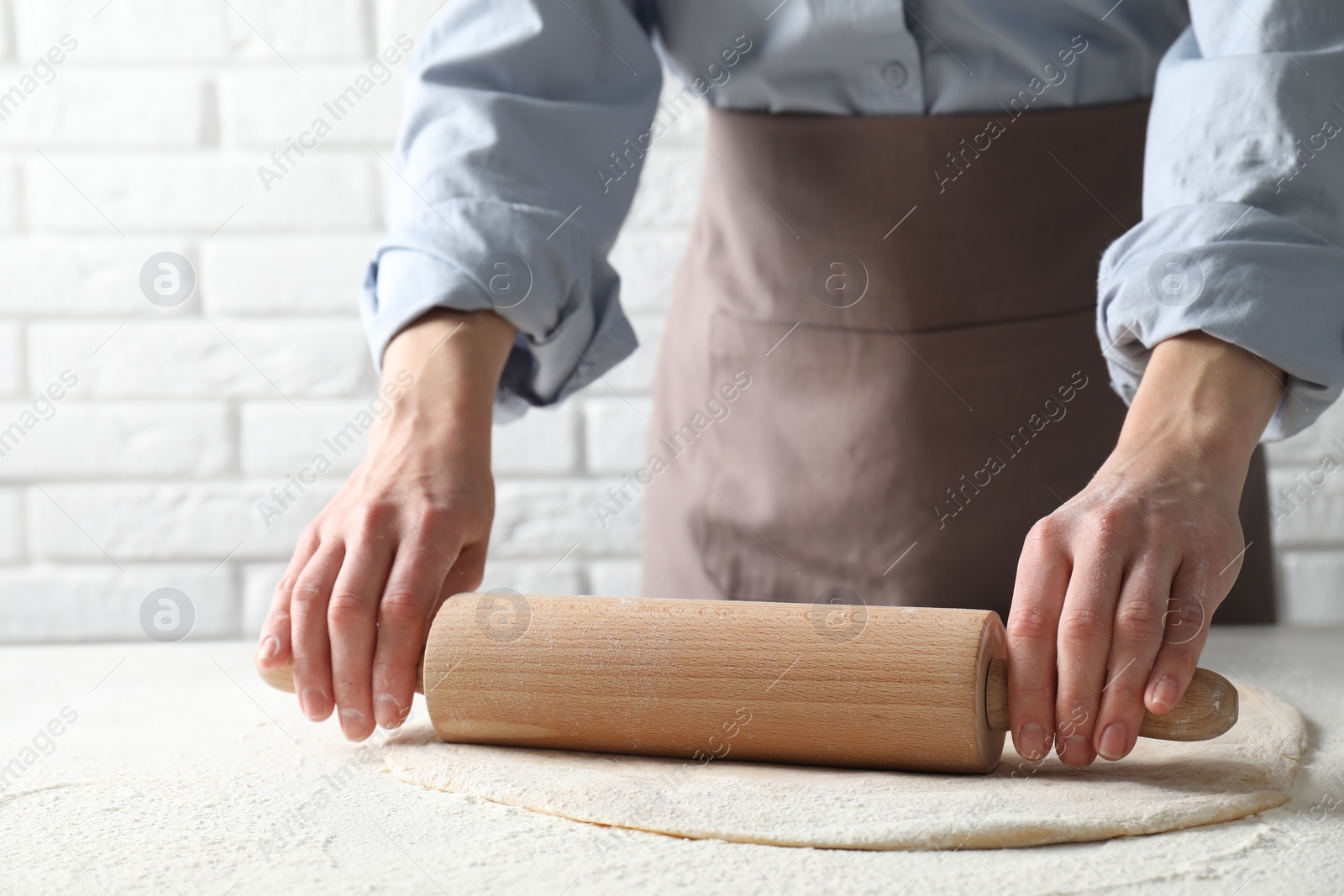 Photo of Woman rolling raw dough at table, closeup