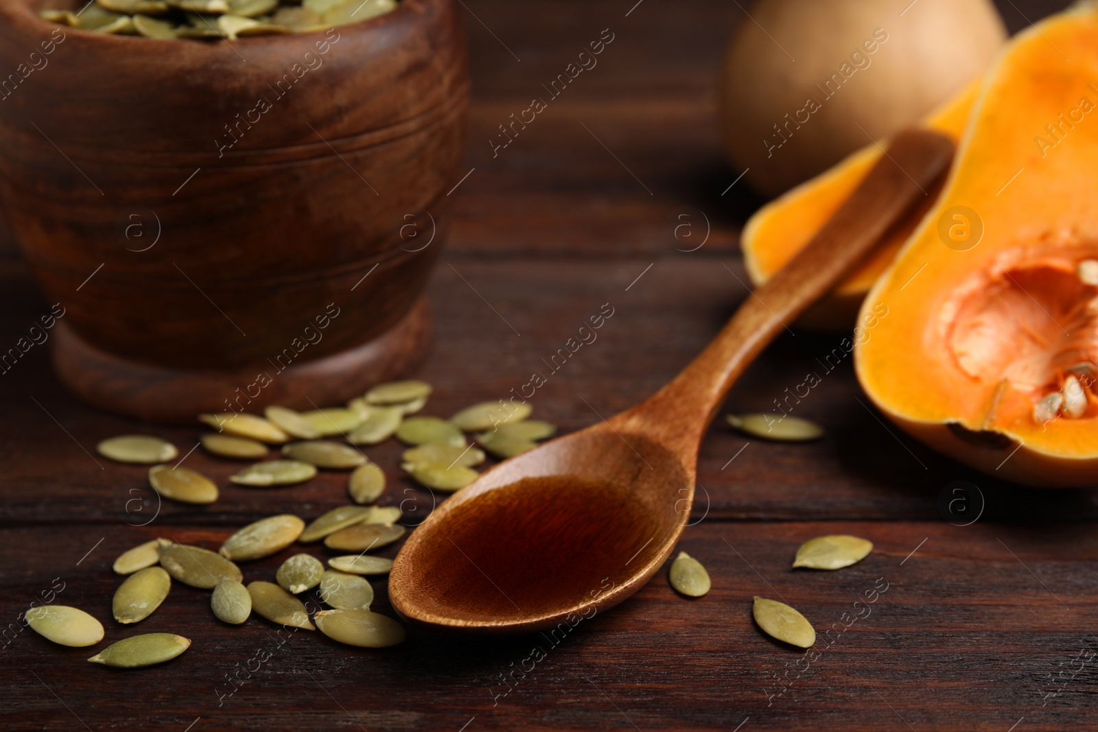 Photo of Spoon with oil and pumpkin seeds on wooden table