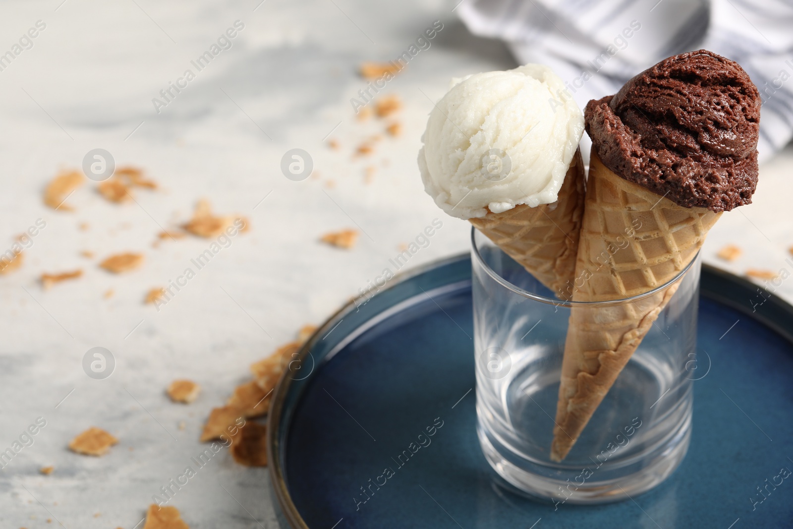 Photo of Tasty ice cream scoops in waffle cones on light table, closeup. Space for text