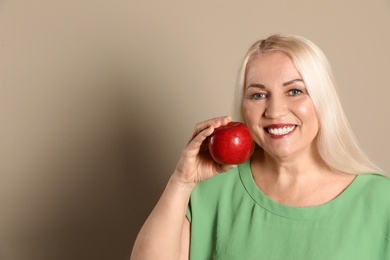 Photo of Smiling woman with perfect teeth and red apple on color background. Space for text