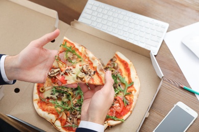 Photo of Office employee having pizza for lunch at workplace, closeup. Food delivery