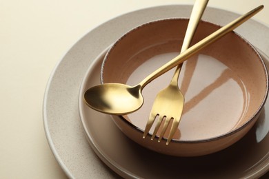 Photo of Stylish empty dishware and cutlery on beige background, closeup