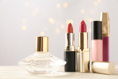 Perfume, lipsticks and lipglosses on white table