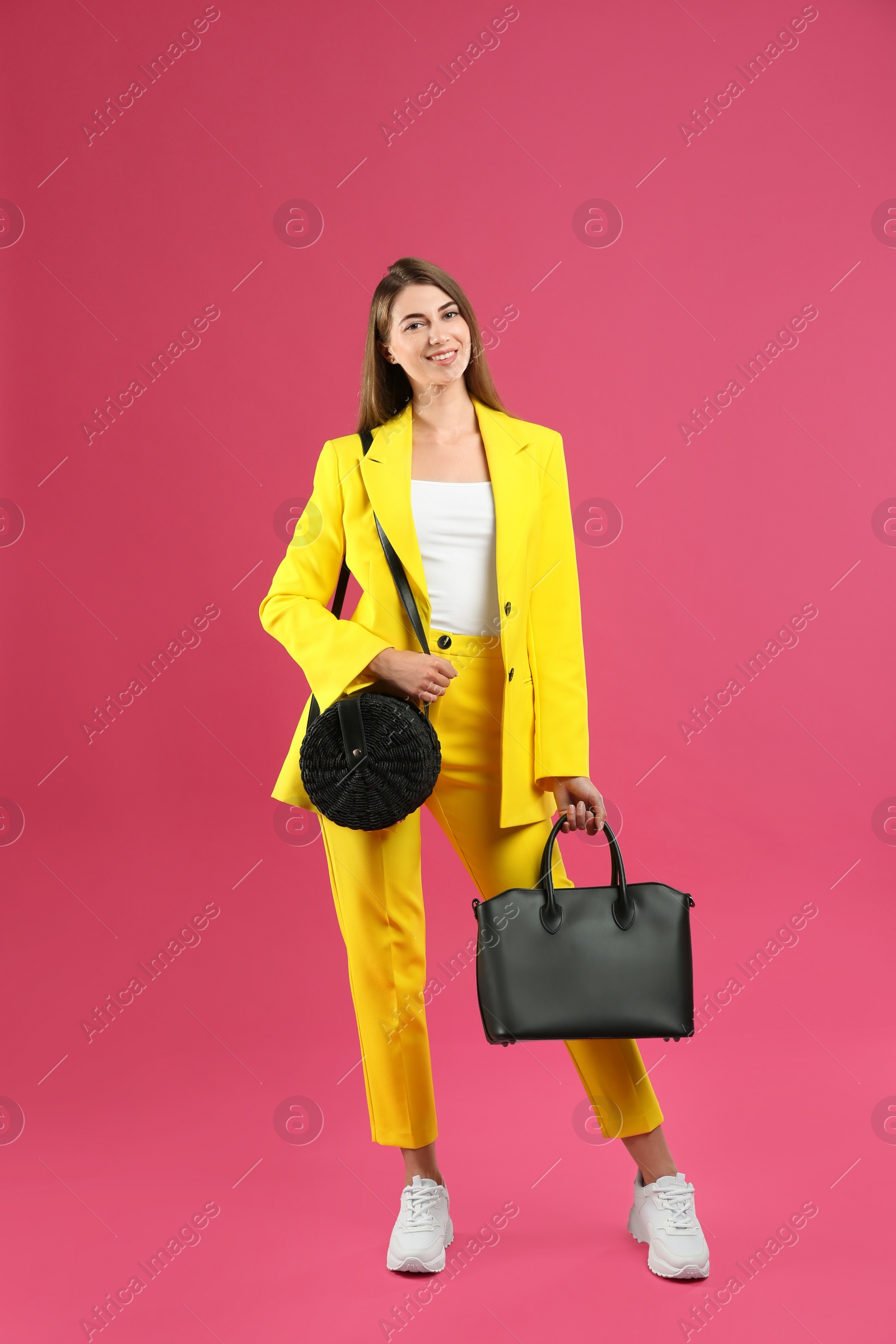 Photo of Beautiful young woman with stylish bags on pink background