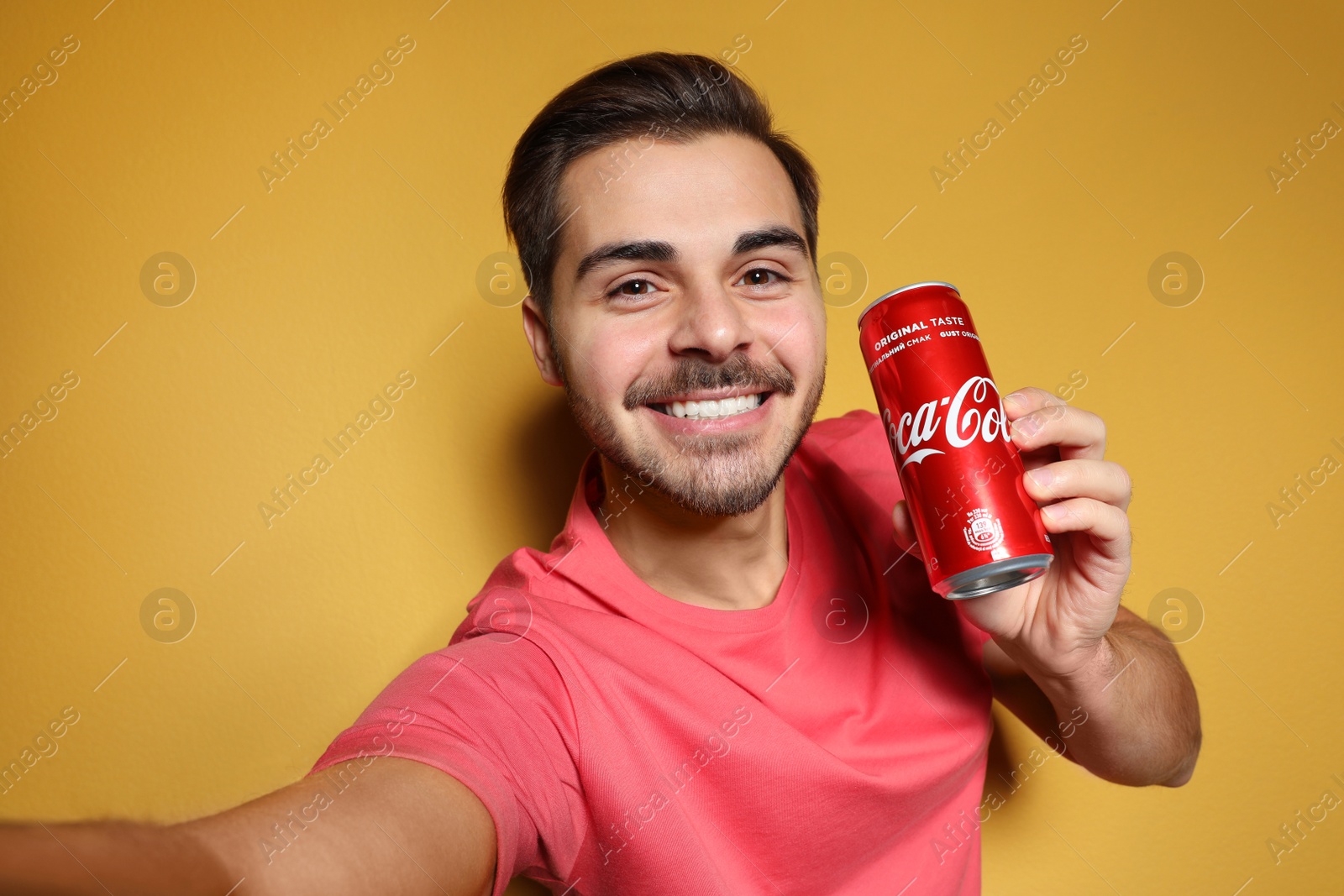 Photo of MYKOLAIV, UKRAINE - NOVEMBER 28, 2018: Young man taking selfie with Coca-Cola can on color background