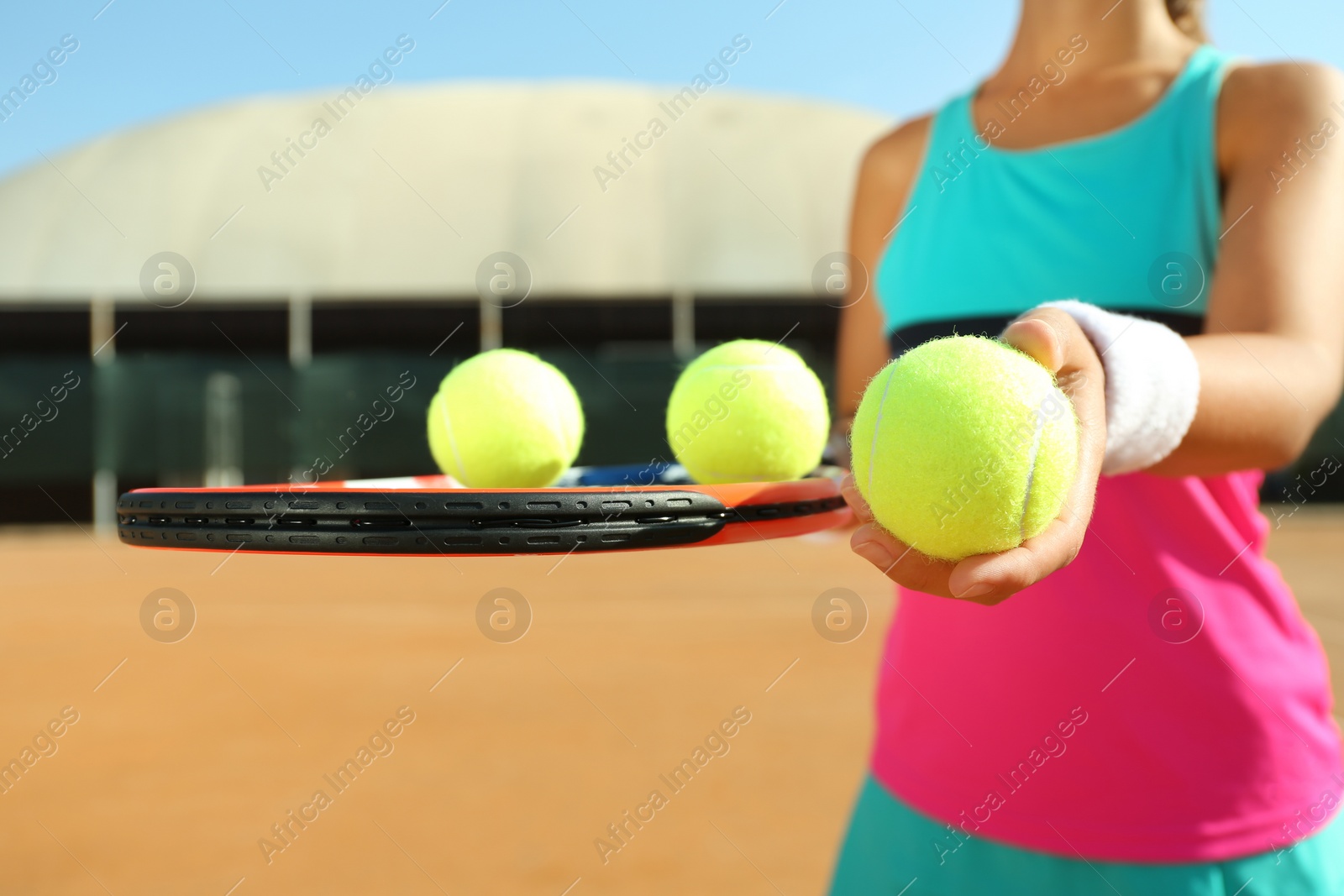 Photo of Sportswoman with racket and tennis balls at court, closeup