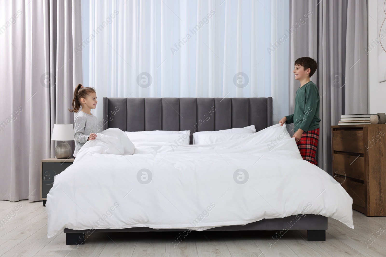 Photo of Brother and sister changing bed linens together in bedroom