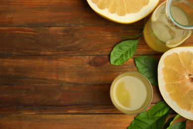 Fresh pomelo juice and fruit on wooden table, flat lay. Space for text