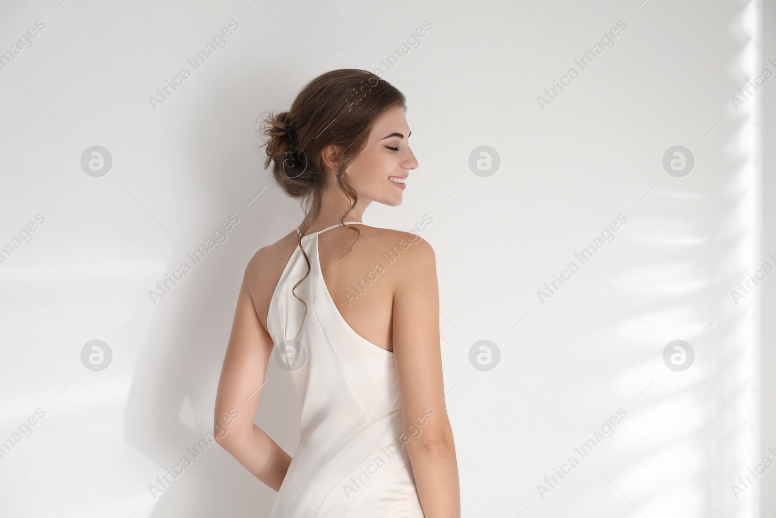 Photo of Young bride wearing beautiful wedding dress on light background