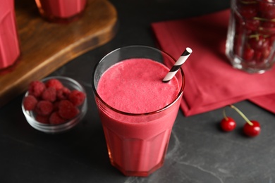 Photo of Tasty fresh milk shake with straw on black table, closeup