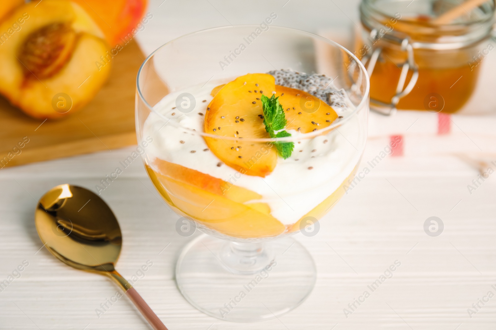 Photo of Tasty peach dessert with yogurt and chia seeds served on white wooden table