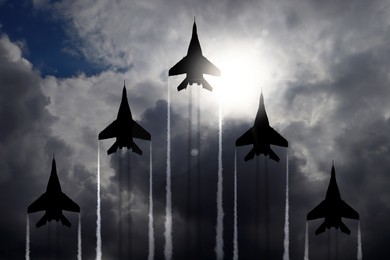 Image of Silhouettes of jet fighters in cloudy sky