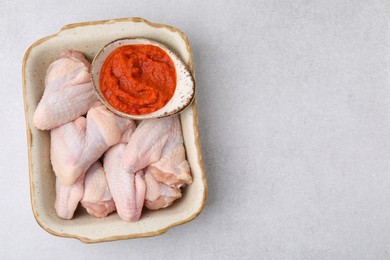 Fresh marinade and raw chicken in baking dish on light table, top view. Space for text