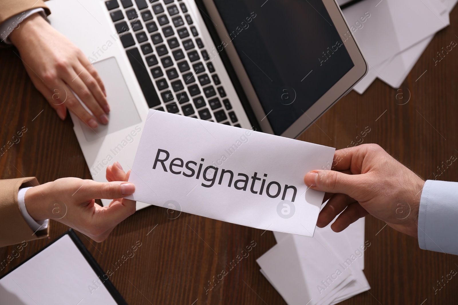 Photo of Employee giving resignation letter to boss in office, top view