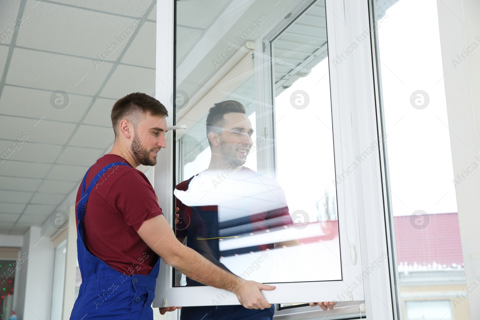 Photo of Construction workers installing plastic window in house