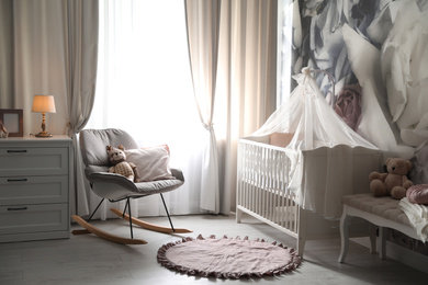 Photo of Baby room interior with stylish crib and floral wallpaper