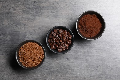 Photo of Bowls of beans, instant and ground coffee on grey table, flat lay
