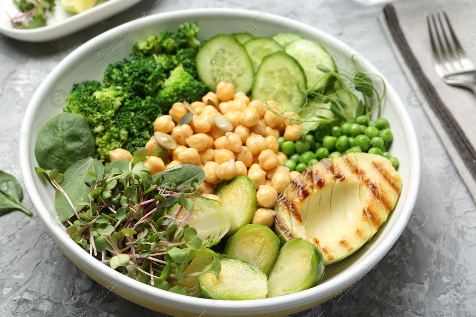 Photo of Healthy meal. Tasty vegetables and chickpeas in bowl on grey table, closeup