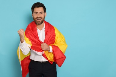 Photo of Man with flag of Spain on light blue background, space for text