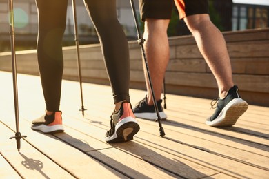 Couple practicing Nordic walking with poles outdoors on sunny day, closeup