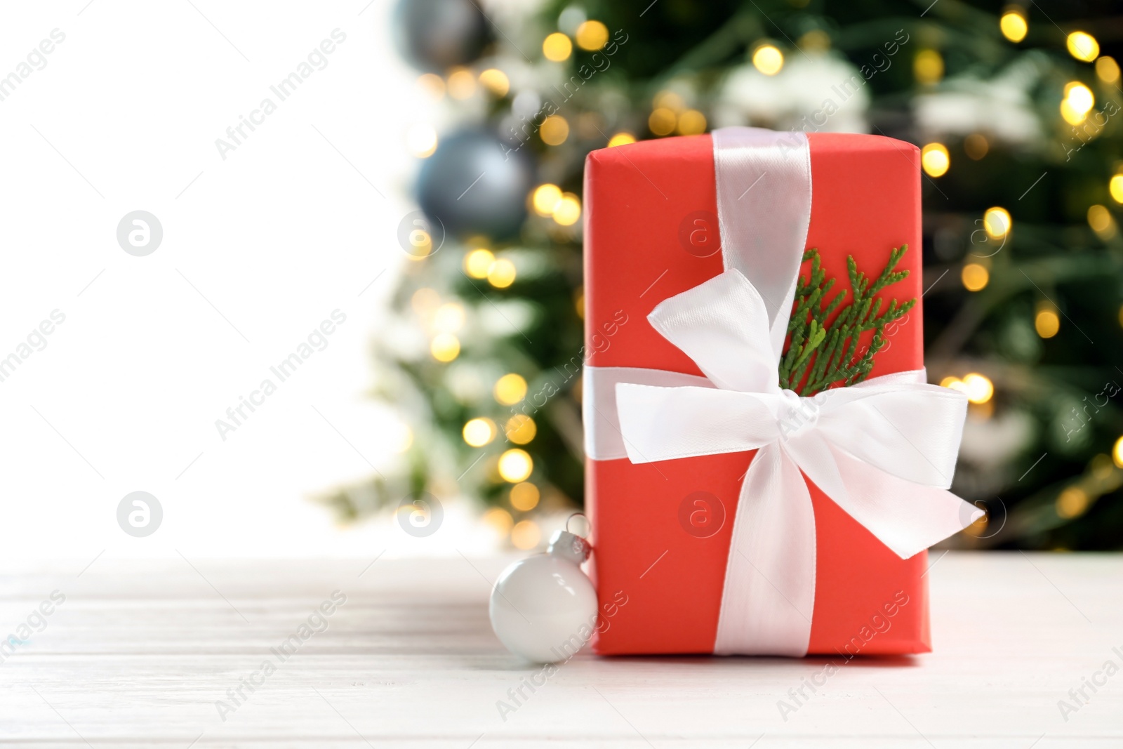 Photo of Beautiful gift box and blurred Christmas tree on background