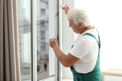 Photo of Mature construction worker repairing plastic window indoors