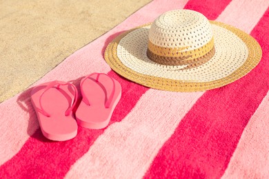 Beach towel with straw hat and slippers on sand